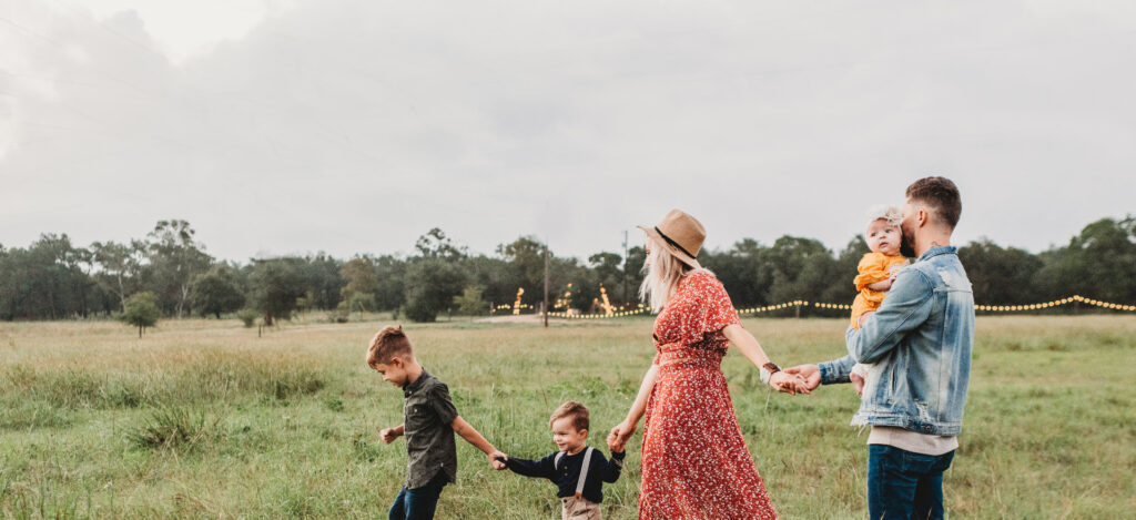 family walking in line holding hands in a grassy field